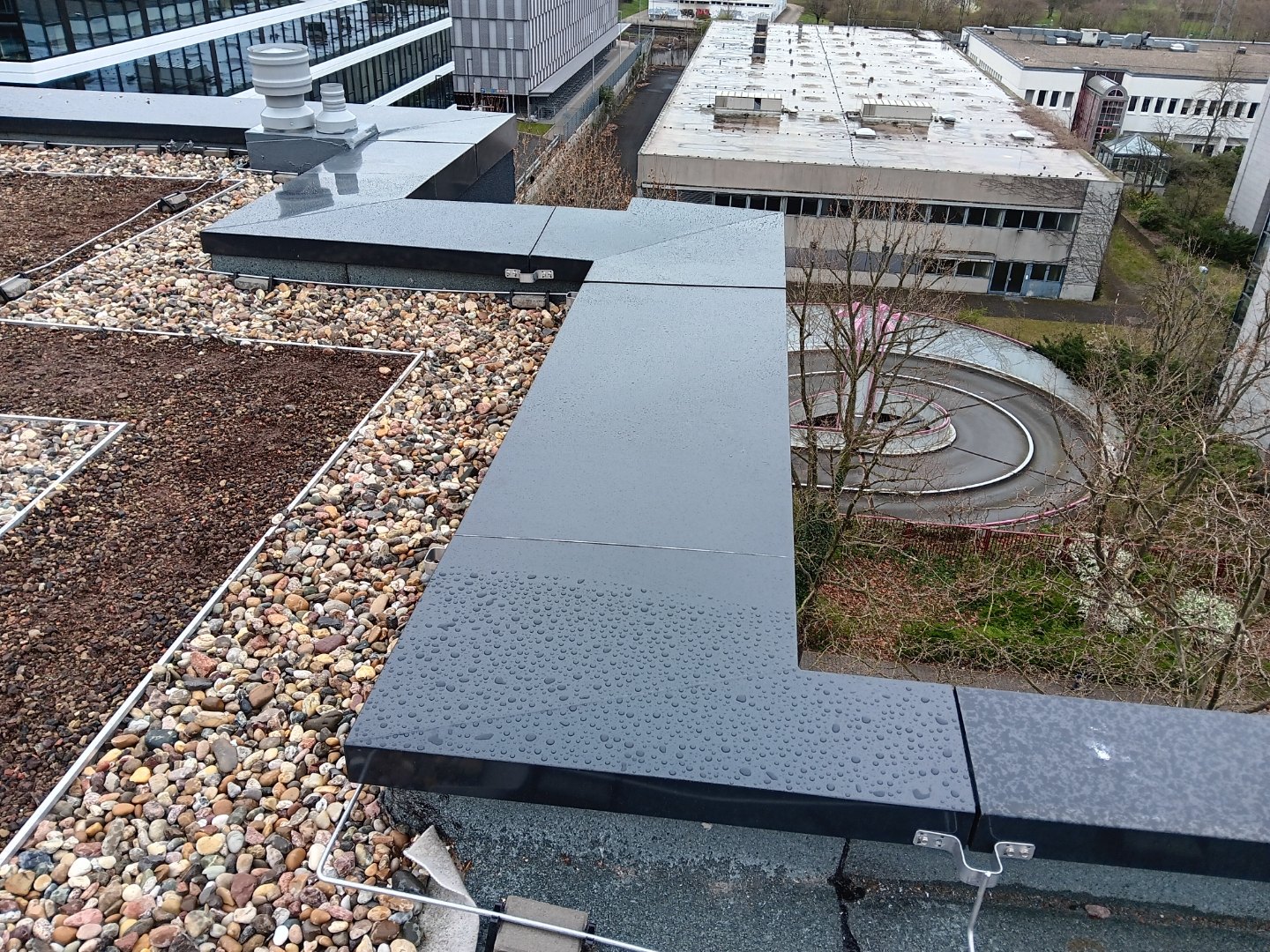 Gründach mit Kiesstreifen und frisch gefalzter Attika-Verblechung auf dem Aparthotel Eschborn, Blick über die Stadt