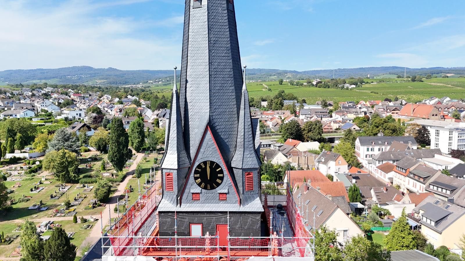 Der Kirchturm von St. Markus Erbach mit frisch eingedeckter Schieferspitze und Turmuhr, dahinter der Rheingau