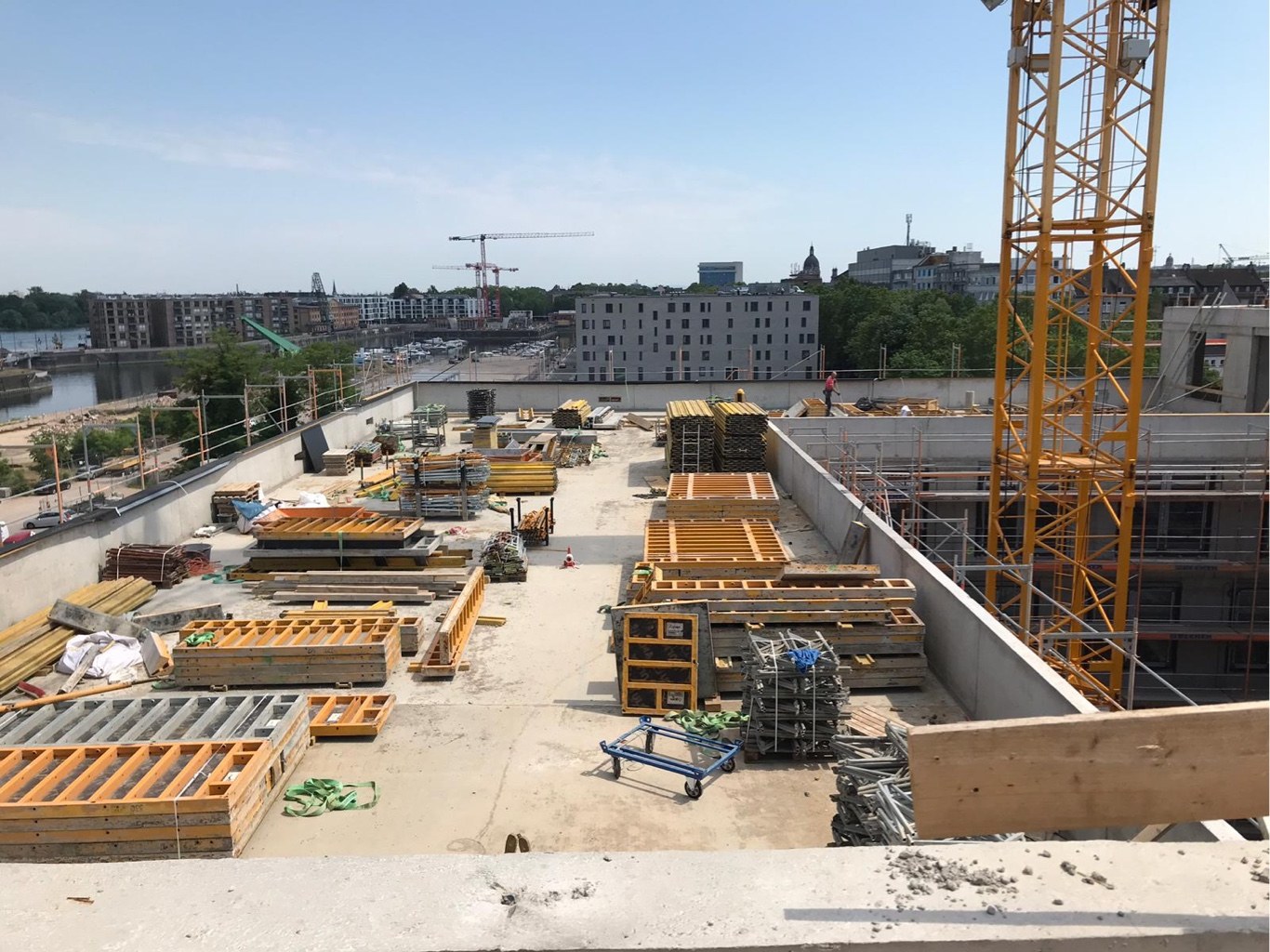 Blick über die Flachdach-Baustelle des Rheinkontors im Zollhafen Mainz mit Kran und Rheinpanorama